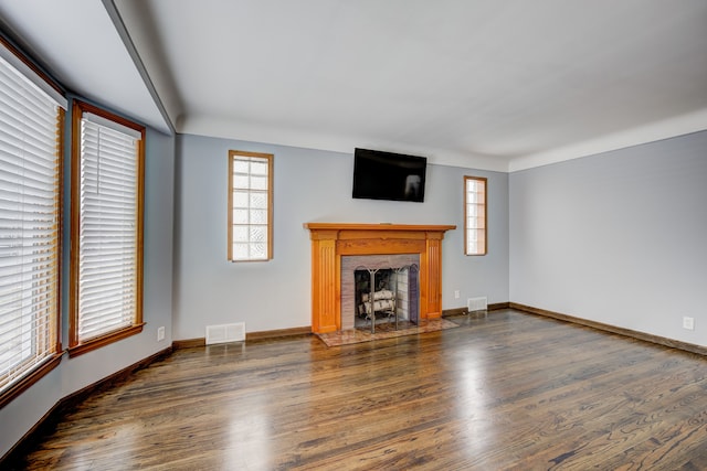 unfurnished living room with a fireplace with flush hearth, wood finished floors, and visible vents