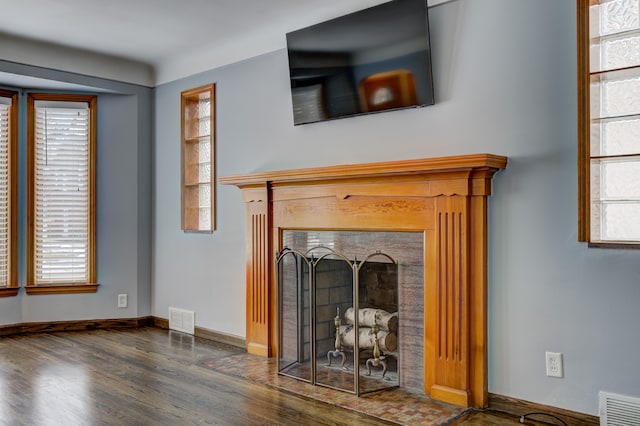 unfurnished living room with a fireplace, wood finished floors, visible vents, and baseboards