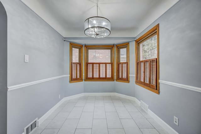 spare room featuring baseboards, tile patterned flooring, visible vents, and an inviting chandelier