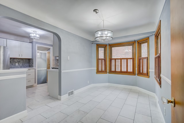 interior space with a chandelier, arched walkways, visible vents, and baseboards