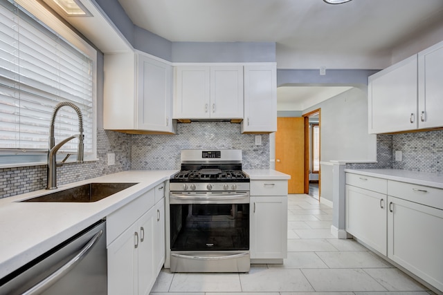 kitchen with stainless steel appliances, a sink, light countertops, and white cabinets