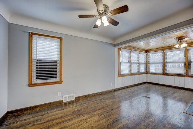 empty room featuring a ceiling fan, baseboards, visible vents, and wood finished floors