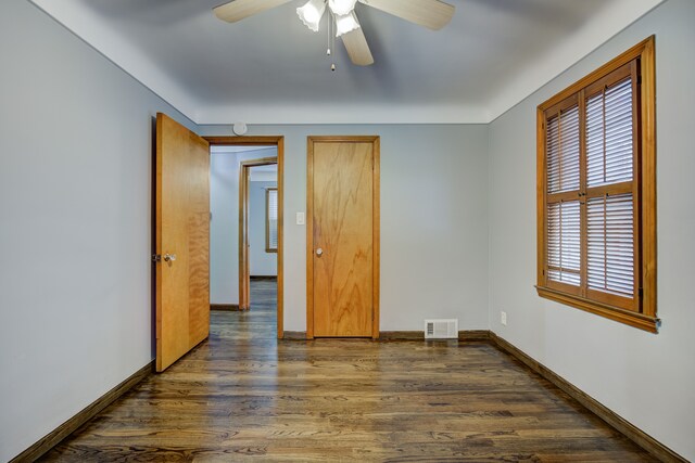 unfurnished bedroom with dark wood-style floors, visible vents, ceiling fan, and baseboards