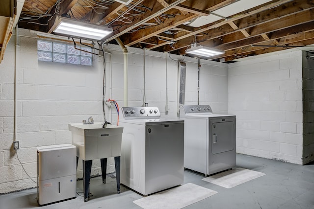 clothes washing area with laundry area, a sink, and washing machine and clothes dryer