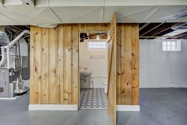 below grade area with concrete block wall, wood walls, a sink, and a wealth of natural light