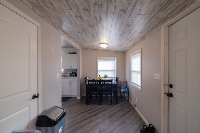 dining area featuring baseboards, wood finished floors, and wooden ceiling