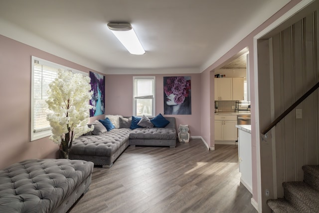 living area with stairway, baseboards, and light wood-style flooring