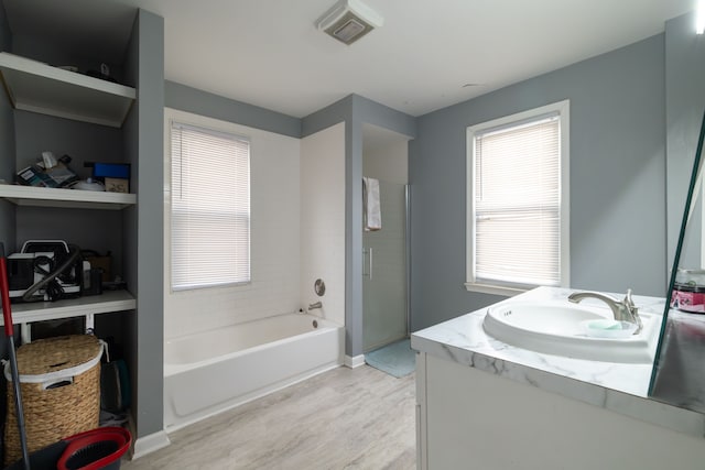 full bathroom featuring a shower stall, a bath, a healthy amount of sunlight, and wood finished floors