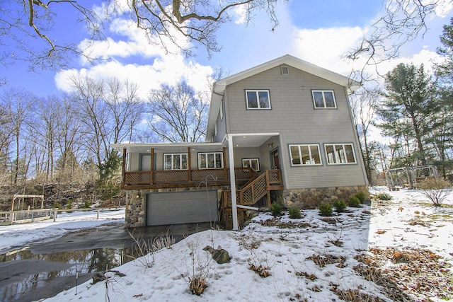 view of front facade featuring a garage, stone siding, stairs, and driveway