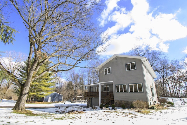 view of snowy exterior featuring a garage and a sunroom