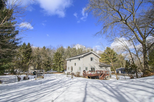 snow covered back of property with a deck