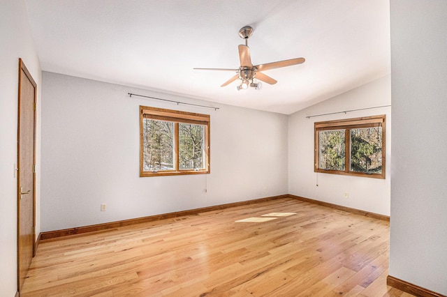 spare room featuring light wood-type flooring, ceiling fan, baseboards, and vaulted ceiling