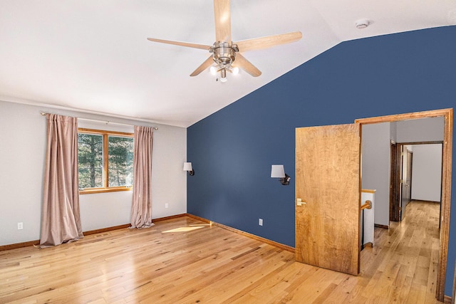 unfurnished room with vaulted ceiling, a ceiling fan, hardwood / wood-style flooring, and baseboards