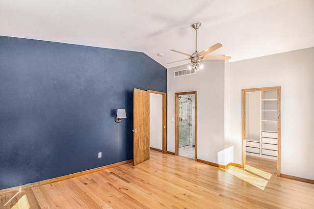 unfurnished bedroom featuring light wood-style floors, visible vents, vaulted ceiling, and baseboards