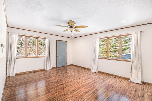 unfurnished room featuring a textured ceiling, ornamental molding, and wood finished floors