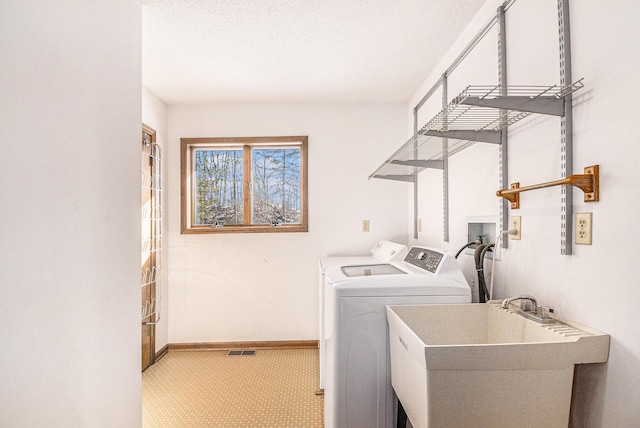 clothes washing area with visible vents, a sink, separate washer and dryer, laundry area, and baseboards