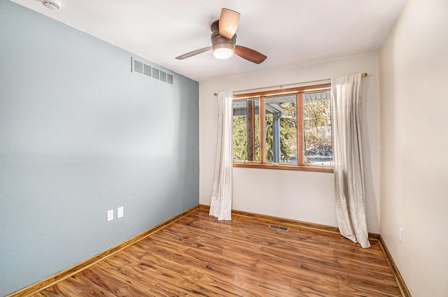 spare room featuring a ceiling fan, wood finished floors, visible vents, and baseboards