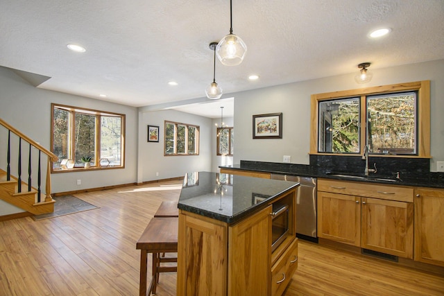 kitchen featuring light wood finished floors, stainless steel dishwasher, a sink, and visible vents