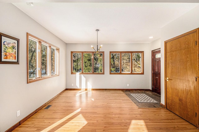 unfurnished room with a notable chandelier, baseboards, visible vents, and light wood-style floors