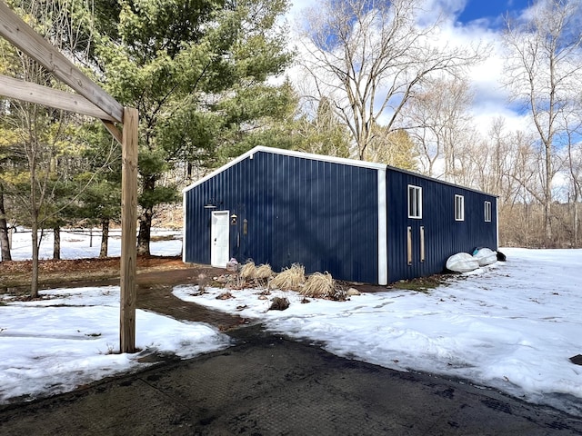 snow covered structure with an outbuilding