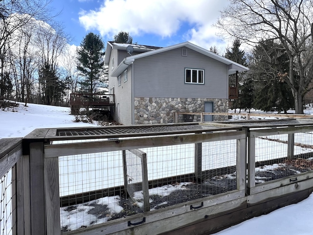 view of snow covered exterior featuring stone siding