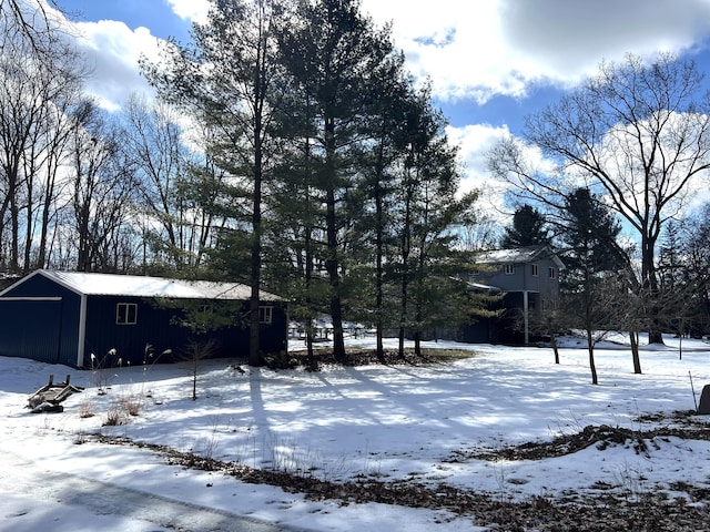 snowy yard featuring a detached garage and an outdoor structure