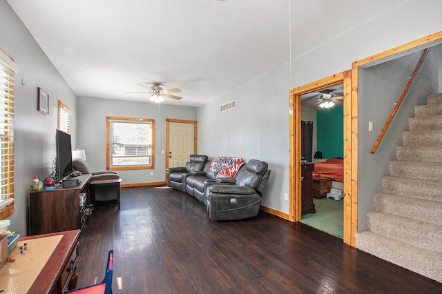 living room featuring baseboards, visible vents, a ceiling fan, dark wood-style floors, and stairs