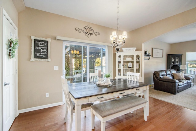 dining room featuring arched walkways, plenty of natural light, wood finished floors, and a notable chandelier