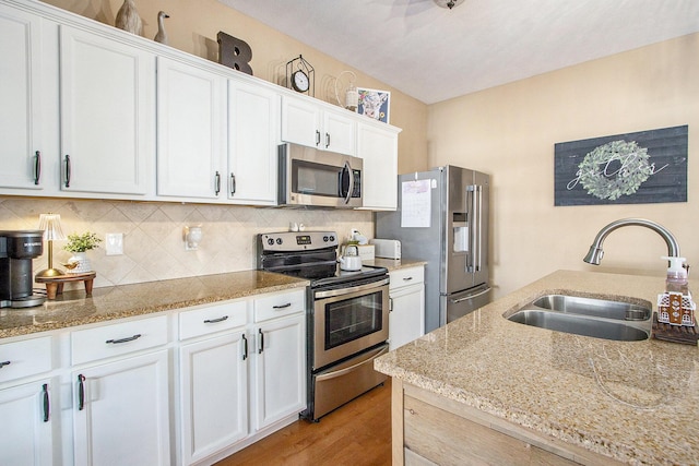 kitchen with stainless steel appliances, white cabinetry, a sink, and tasteful backsplash