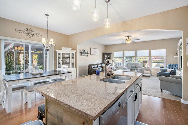 kitchen featuring arched walkways, open floor plan, a sink, and dishwasher