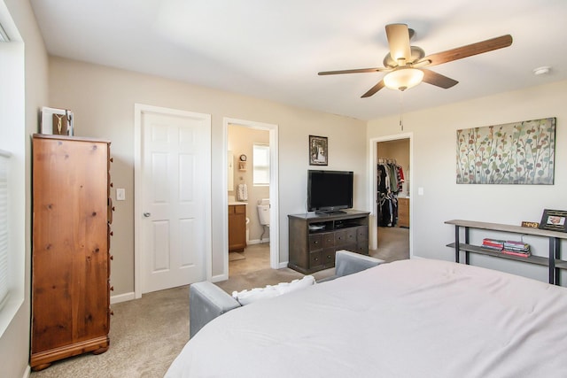 bedroom with baseboards, light colored carpet, ensuite bathroom, a spacious closet, and a closet