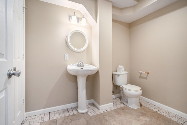 half bath with a sink, toilet, and baseboards