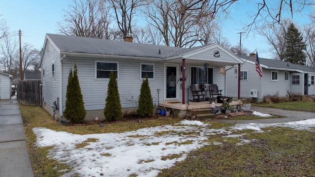 view of front of home featuring covered porch, roof with shingles, and a chimney