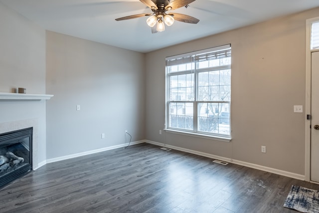 unfurnished living room featuring dark wood-style floors, visible vents, a tiled fireplace, ceiling fan, and baseboards