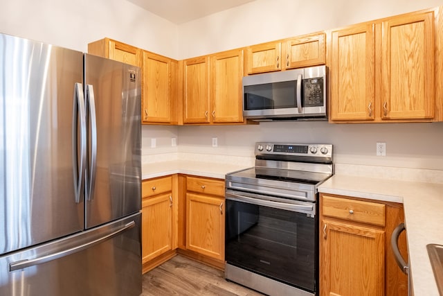 kitchen featuring light wood-style flooring, stainless steel appliances, and light countertops