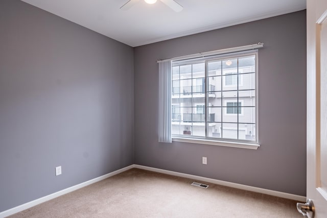 carpeted empty room with baseboards, visible vents, and ceiling fan