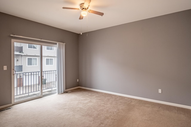 carpeted spare room with visible vents, baseboards, and ceiling fan