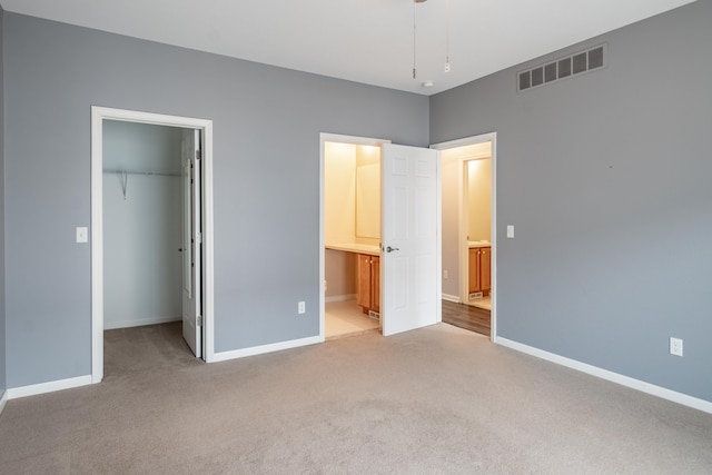 unfurnished bedroom featuring carpet floors, a closet, visible vents, a spacious closet, and baseboards