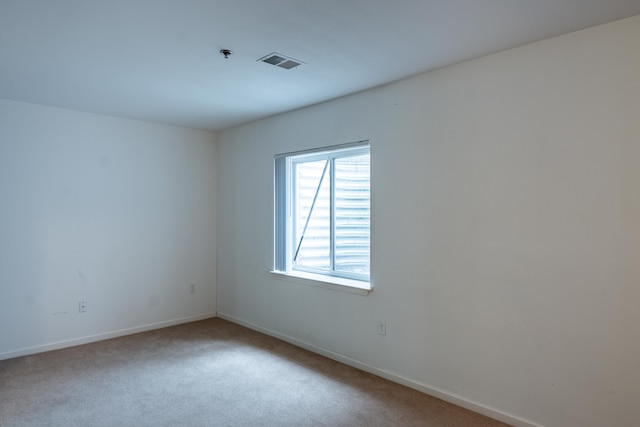 empty room featuring carpet, visible vents, and baseboards