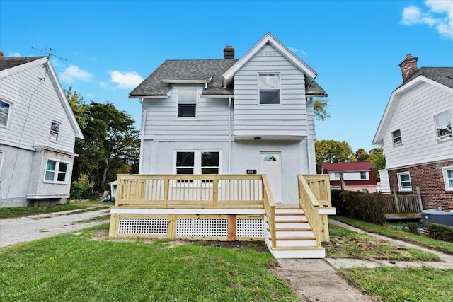 rear view of property featuring a chimney, roof with shingles, a deck, and stucco siding