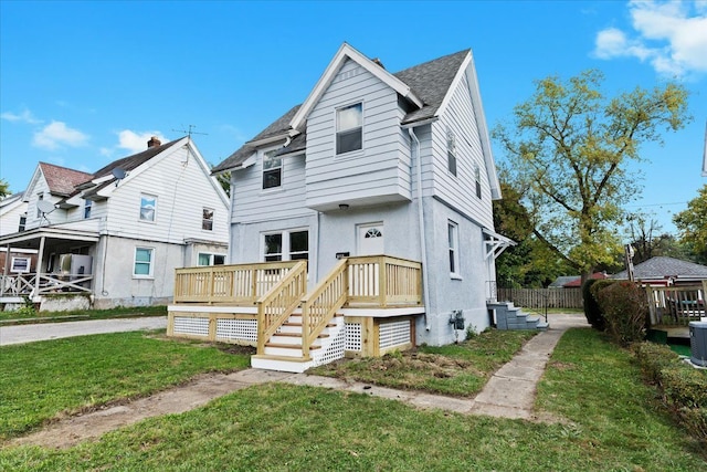 view of front of house featuring a deck, roof with shingles, a front yard, and stucco siding