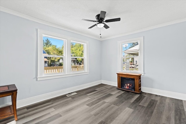 spare room with visible vents, a glass covered fireplace, a textured ceiling, wood finished floors, and baseboards