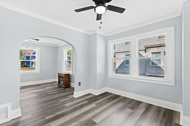 spare room featuring baseboards, visible vents, a ceiling fan, wood finished floors, and crown molding