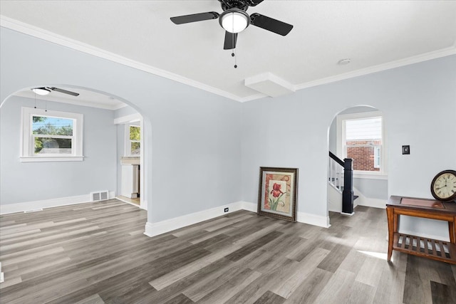 unfurnished living room featuring a healthy amount of sunlight, visible vents, arched walkways, and wood finished floors