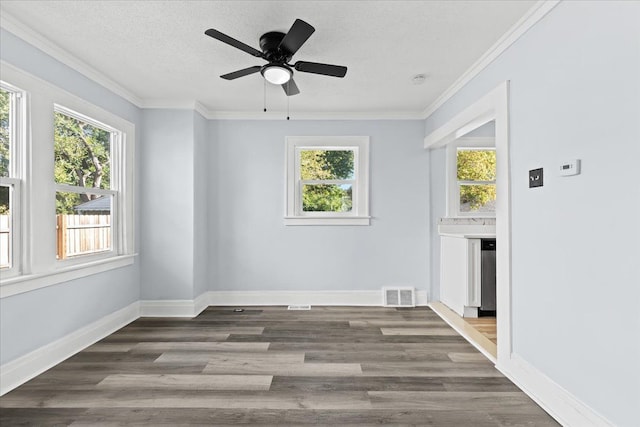 empty room featuring baseboards, visible vents, wood finished floors, crown molding, and a textured ceiling