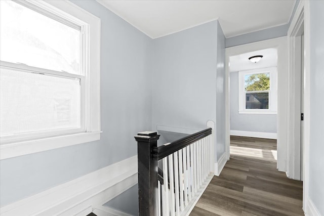 corridor featuring baseboards, dark wood finished floors, and an upstairs landing