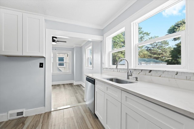 kitchen with crown molding, light countertops, visible vents, stainless steel dishwasher, and a sink