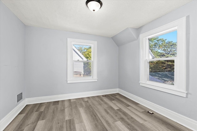 bonus room with visible vents, baseboards, wood finished floors, vaulted ceiling, and a textured ceiling