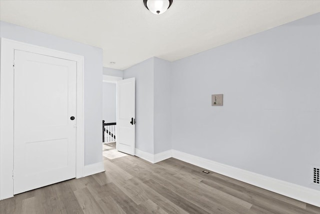 spare room with baseboards and wood finished floors