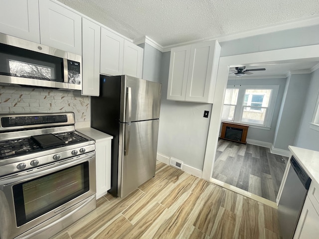 kitchen with white cabinets, light wood-style flooring, stainless steel appliances, and light countertops